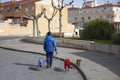 A man walks three medium-sized dogs around the city, two of them carry pet clothes for the cold