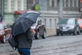 A man walks under an umbrella along the road and tram tracks Royalty Free Stock Photo