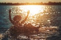 A man ware hat and he is on swim tube in the water. He is hands up to make water splash Royalty Free Stock Photo