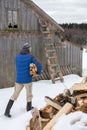 Man carries an armful of firewood, against the backdrop of a barn, in the countryside, on a winter day. Heating season Royalty Free Stock Photo