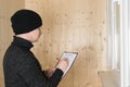 A man in warm clothes and a hat writes down the results of the work on warming the loggia Royalty Free Stock Photo