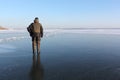 Man in warm clothes walking along the thin ice of a frozen river in the evening Royalty Free Stock Photo