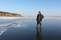 Man in warm clothes walking along the thin ice of a frozen river in the evening Royalty Free Stock Photo
