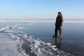 Man in warm clothes walking along the thin ice of a frozen river in the evening Royalty Free Stock Photo