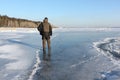 Man in warm clothes walking along the thin ice of a frozen river in the evening Royalty Free Stock Photo