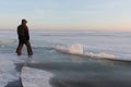 Man in warm clothes walking along the thin ice of a frozen river Royalty Free Stock Photo