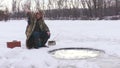 Man pulls a fish out of a river in winter.