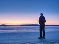 Man in warm suit gesture to morning horizon. Hiker stay on ice