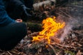 Man warms his hands on fire. Burning wood at evening in the forest. Campfire at touristic camp at nature. Barbeque and Royalty Free Stock Photo