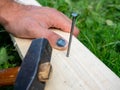 The man was hammering a nail into the board but hit on the finger of his hand. Hematoma, injury, accident at work. An insurance