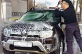 A man washes a car at a contactless car wash, a man washes a brown car