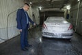 man washes a car in a box contactless car wash self-service with a water gun in manual self-service washing station