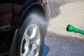 Man washes car wheel. Male hand holds pink sponge with soapy foam for cleaning. Royalty Free Stock Photo