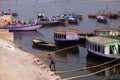 Man washes clothes on the banks of the river Ganges with old boats around