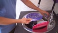 A man washes dishes with a sponge. A person washes off the detergent with water from the dishes. Close-up of the hand of