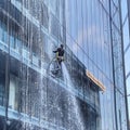 a man washes the glass of a tall building with floor-to-ceiling windows Royalty Free Stock Photo