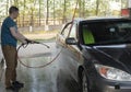 A man washes his car with pressurized water in a car wash