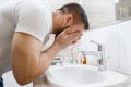 Man washes his face in bathroom, morning hygiene Royalty Free Stock Photo