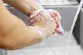 A man washes his hands with soap under the tap under running water close-up. Health, and hygiene concept. Royalty Free Stock Photo