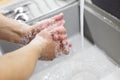 A man washes his hands with soap under the tap under running water close-up. Health, and hygiene concept. Royalty Free Stock Photo