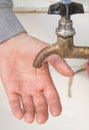A man washes his hands with tap water from an old authentic copper tap, vertical frame, close-up Royalty Free Stock Photo