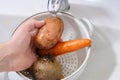 A man washes vegetables under the tap of water in the kitchen. Close-up