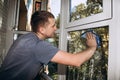 A man washes windows at home using a blue rag, cleaning the house close-up. Selective focus Royalty Free Stock Photo