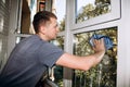 A man washes windows at home using a blue rag, cleaning the house close-up. Selective focus Royalty Free Stock Photo