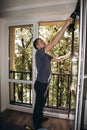 The man washes the windows at home using a cordless window cleaner, cleaning the house. Selective focus Royalty Free Stock Photo