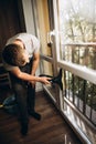 A man washes windows at home using a cordless window vacuum cleaner. Selective focus