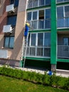 A man washes windows on the street standing on the stairs. Cleaning company. Worker in blue overalls washes a window of a multi-