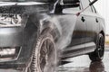 A man is washing a car at self service car wash. High pressure vehicle washer machine sprays foam. Royalty Free Stock Photo