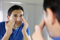 Man washing face with facial cleanser face wash soap looking at mirror in bathroom at home. Men skin care concept