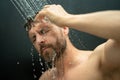 Man washing hair in bathroom. Guy bathing shower head in bathtub. Male face in shower. Man taking shower in bathroom Royalty Free Stock Photo