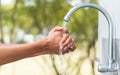 Man washing hand after working with outdoor faucet sink, cleaning hygiene protection concept with flowing water and green forest Royalty Free Stock Photo