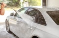 Man washing his car in self serve carwash, detail on water jet stream spraying to the side