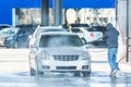 Man washing his car with using a high compression pressure water jet. Washing his car in a self-service car wash station Royalty Free Stock Photo
