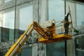 A man washing large windows and facade of tall corporate building with a mop.