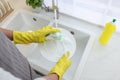 Man washing plate in kitchen sink, closeup