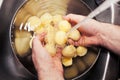 Man washing raw peeled potatoes under running water Royalty Free Stock Photo