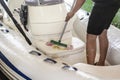 Man washing white inflatable boat with brush and pressure water system at garage. Ship service and seasonal maintenance concept Royalty Free Stock Photo