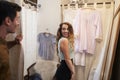 Man watches his partner trying on clothes in changing room