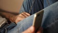 A man watches a porn video on his smartphone and touches his genitals through his blue jeans. A guy stroking his crotch