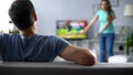 Man watching football match ignoring conflict with woman, crisis in relations