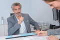 Man watching lady sign paperwork