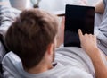 man watching media content in a tablet sitting on a couch