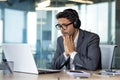 Man watching sports match inside office at workplace, cheering, businessman in headphones and laptop sitting at table Royalty Free Stock Photo