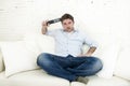 Man watching television at home living room sofa with remote control looking very interested Royalty Free Stock Photo