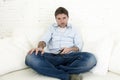 Man watching television at home living room sofa with remote control looking very interested Royalty Free Stock Photo