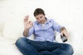 Man watching television at living room sofa with remote control smiling giving okay hand sign Royalty Free Stock Photo